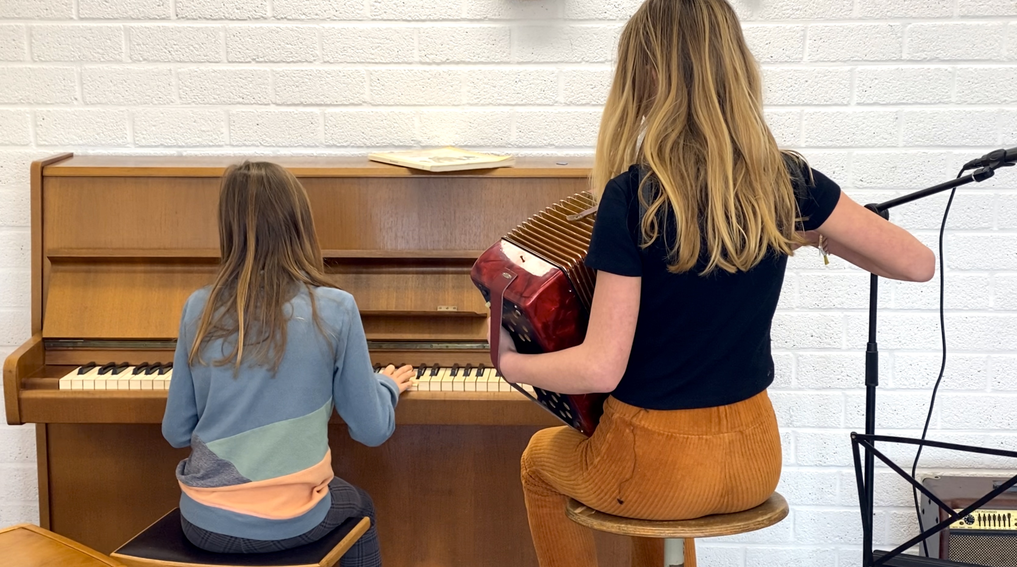 Foto van twee leerlingen achter de piano met accordeon