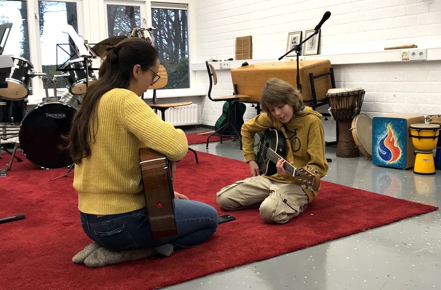 Foto van docent en leerling die gitaar spelen