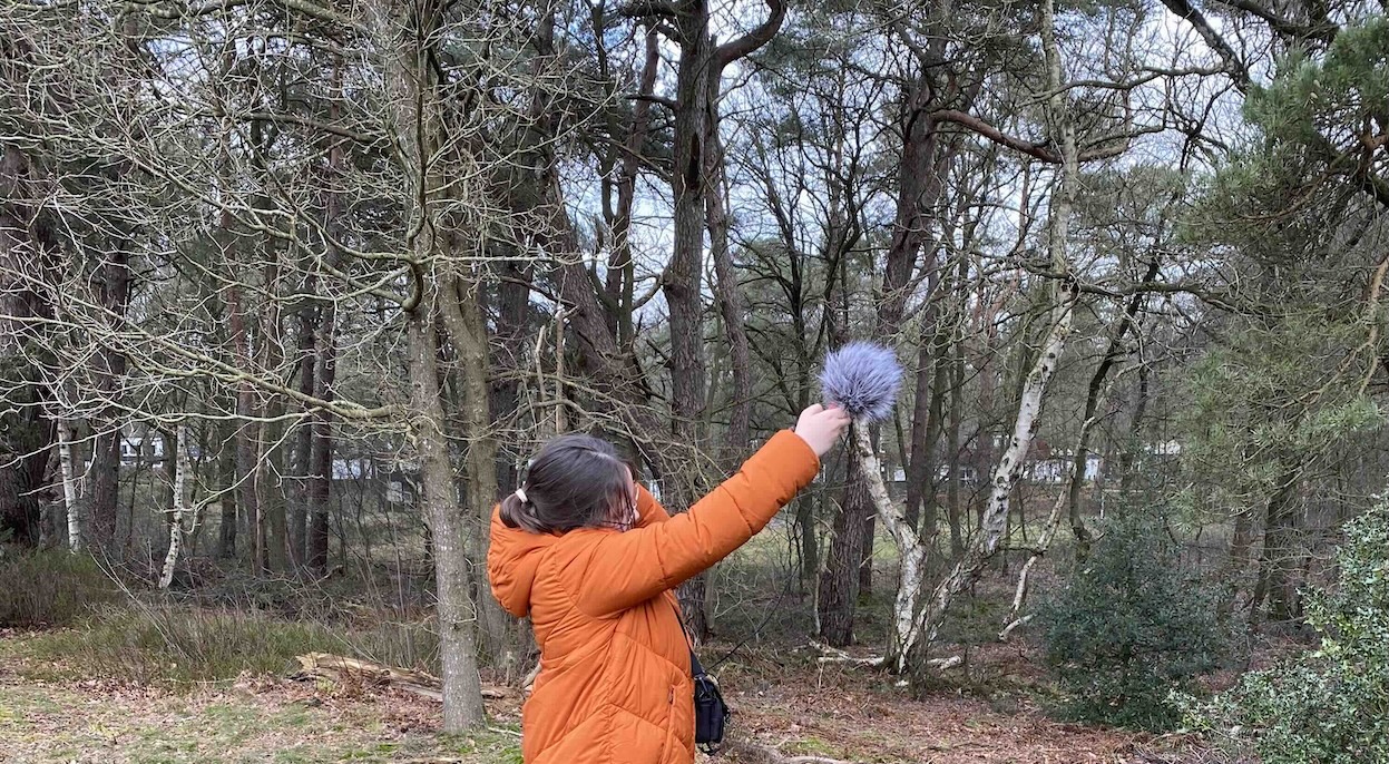 Foto van leerling die geluiden in het bos opneemt