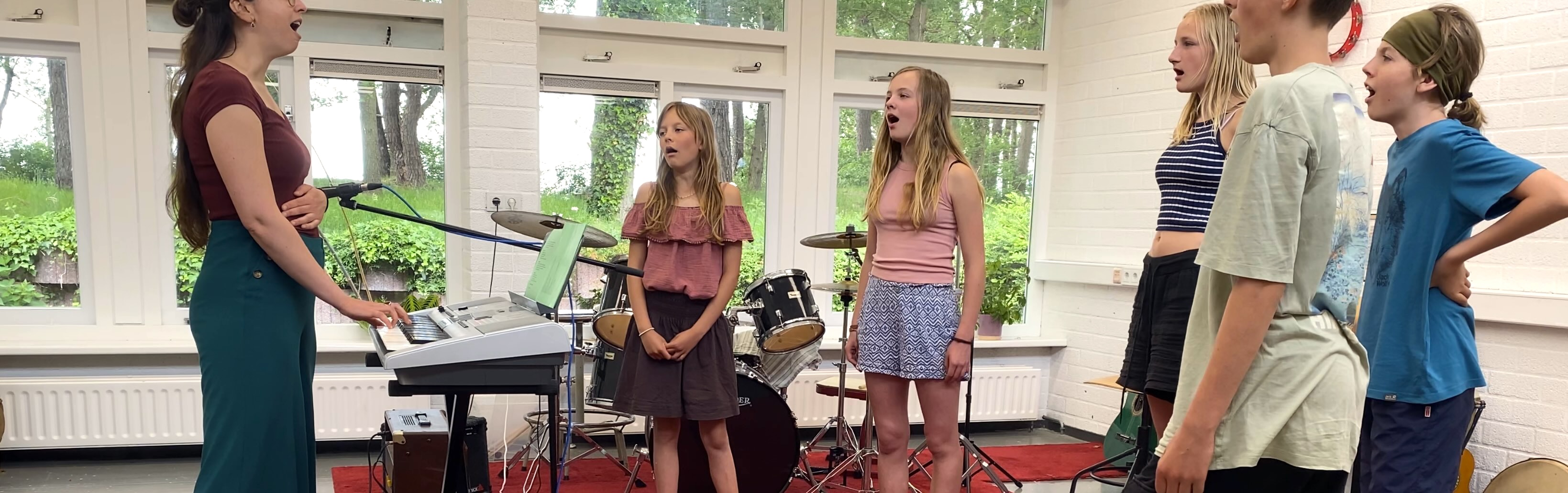 Foto van docent en leerling die zingen bij de piano